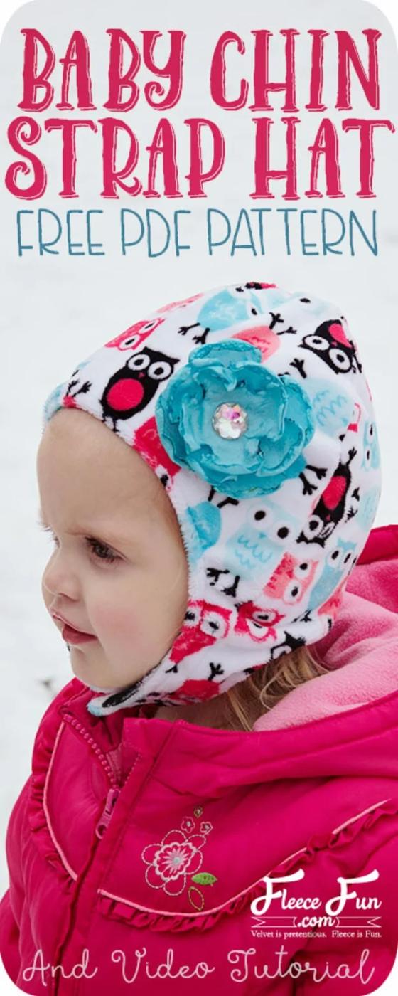 Toddler in a white owl print fleece hat with ear flaps, a chin strap and a turquoise fabric flower, in snow