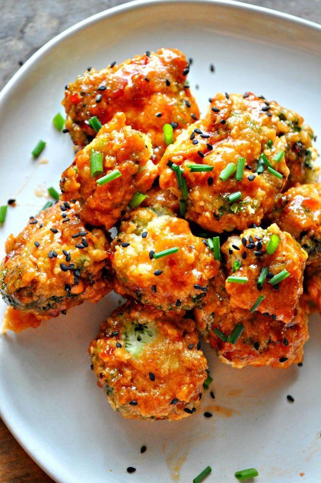 Breaded vegan popcorn broccoli in spicy orange glaze on a white plate with black sesame seeds and chives