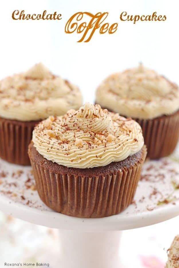 Chocolate coffee cupcakes with swirled pale coffee buttercream dusted with cocoa on a white pedestal cake stand