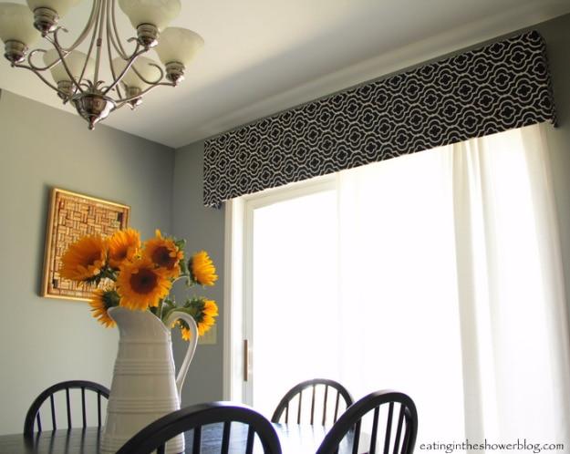 Black and white geometric pelmet box above a sliding door in a dining room, with white curtain panels hanging below