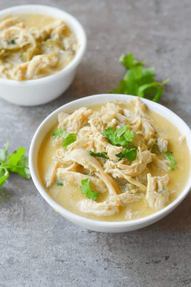 Keto white chicken chili with shredded chicken and cilantro in a small white bowl on a gray stone surface