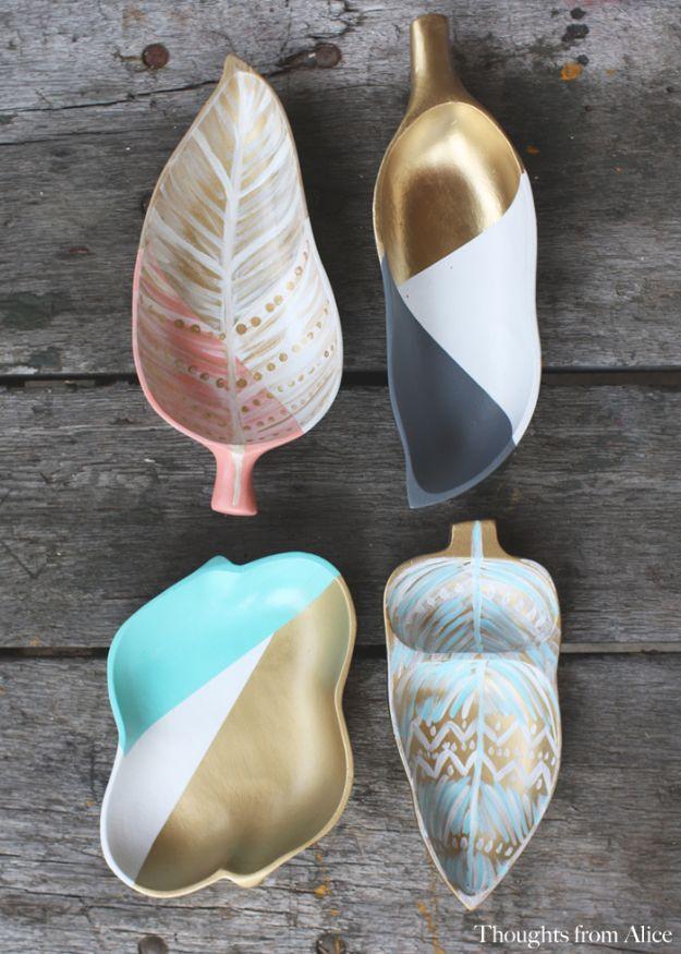 Four wooden leaf shaped trinket dishes painted in color blocks of gold, teal, gray and blush on wood