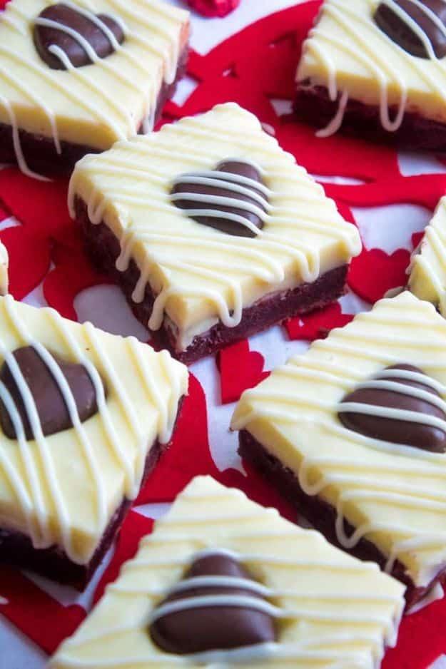 White chocolate fudge red velvet brownies topped with white fudge, cream cheese drizzle and chocolate hearts