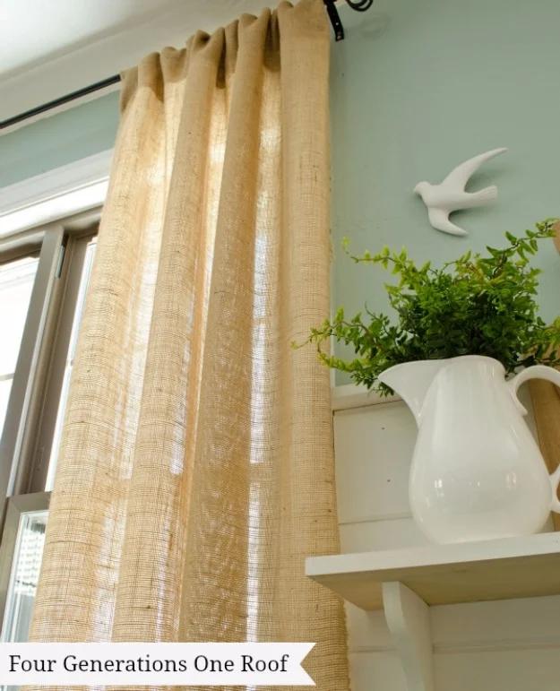 DIY curtain panel in natural burlap hanging from a black rod beside a white shelf holding a pitcher and a bird ornament