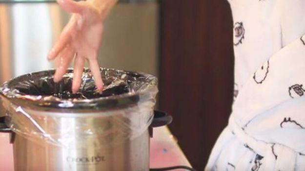 Day spa at home, a hand testing the water in a plastic lined slow cooker beside a woman in a patterned robe