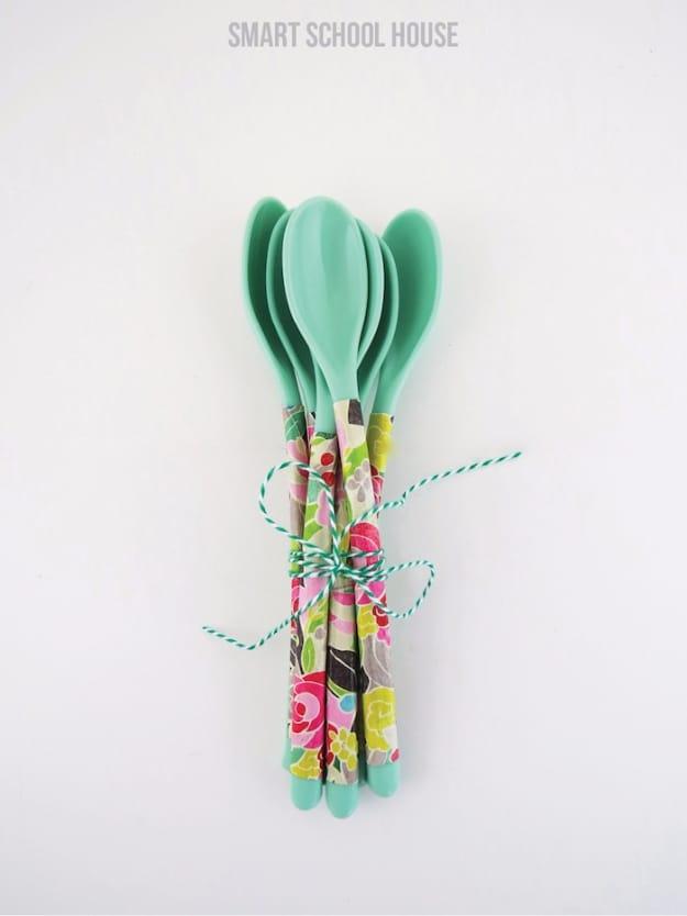 Four metal spoons with tiny flowers painted along the handles, tied with twine beside a cup of black tea