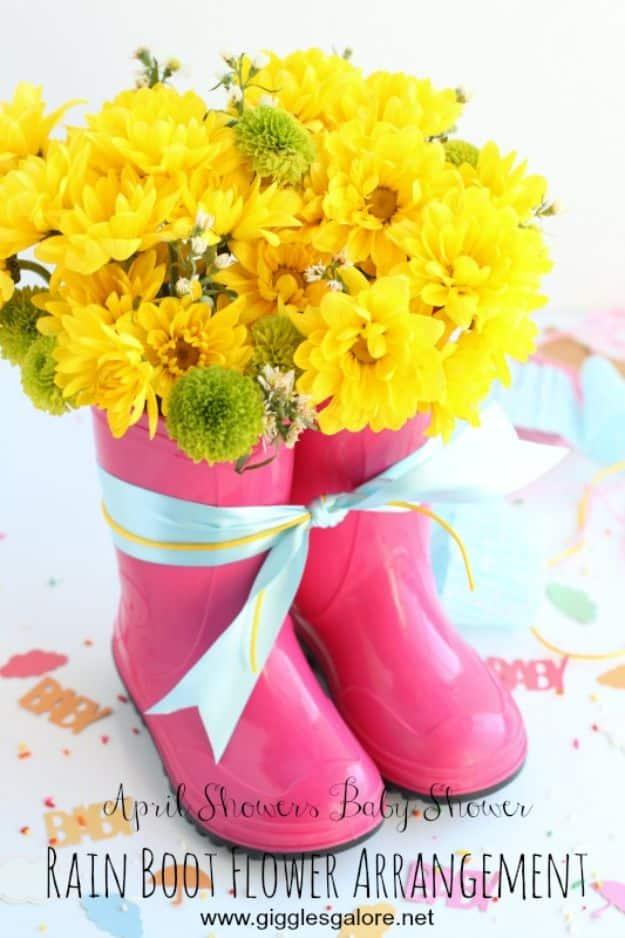 Rain boot flower arrangement, two small pink rain boots tied with a pale blue ribbon and filled with yellow flowers