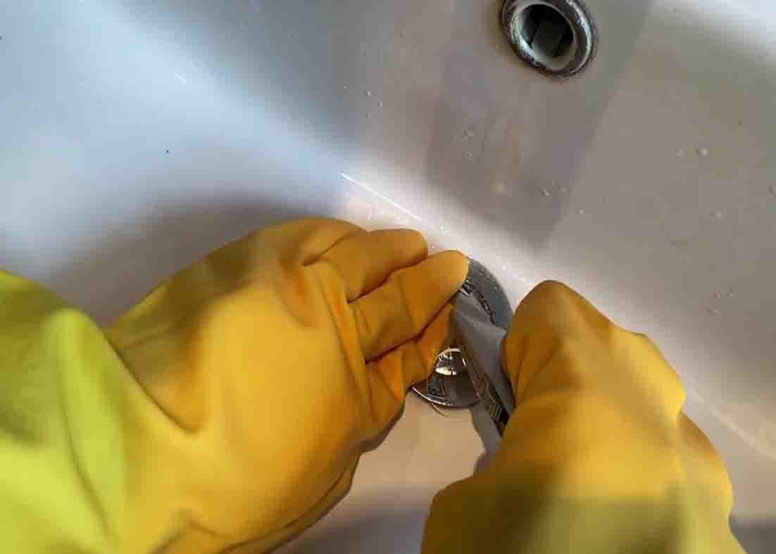 Inserting the dental floss strip slowly to the stuck pop-up sink plug