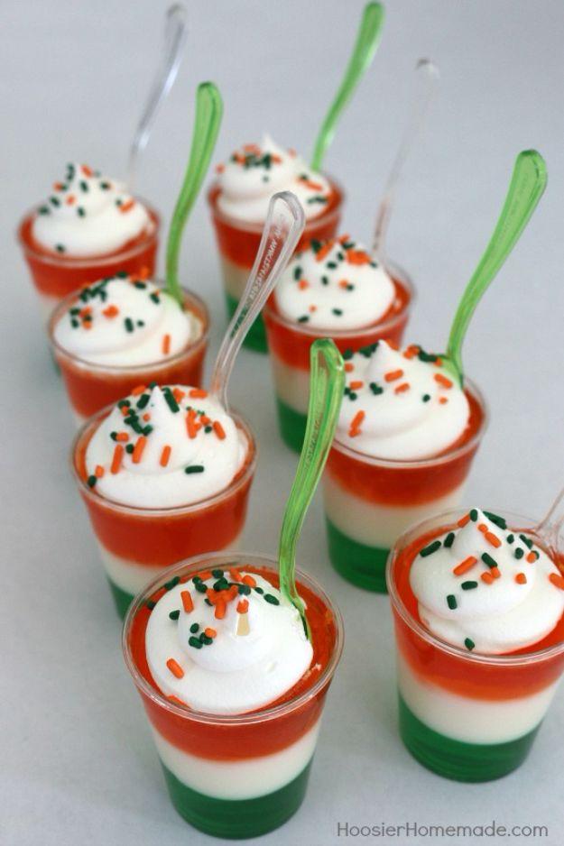 Irish flag jello shots in plastic cups with green, white and orange layers, whipped topping and sprinkles