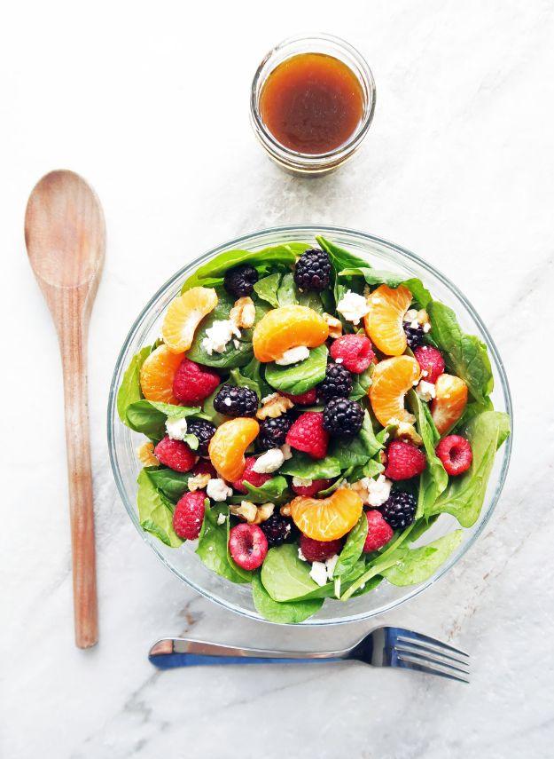 Berry orange spinach salad in a glass bowl with spinach, mandarin segments, raspberries and crumbled feta