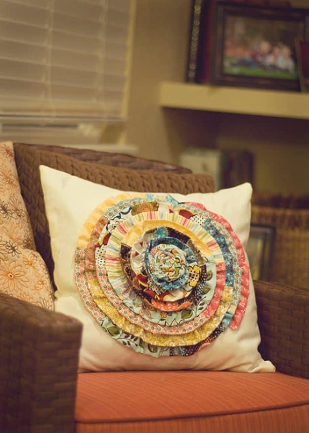 Cream throw pillow topped with a large spiral rosette coiled from fabric scrap strips, on a brown wicker chair