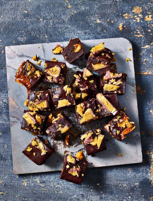 Crunchie bar and salted caramel brownies cut into pieces on slate with golden honeycomb shards on top