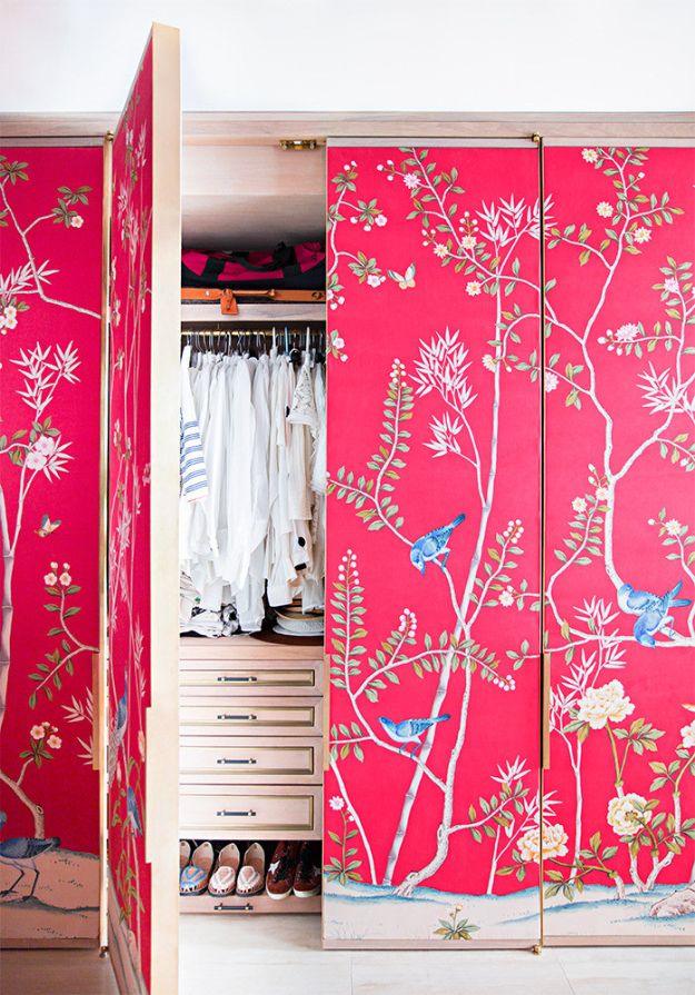 Folding closet doors covered in hot pink and blue chinoiserie wallpaper standing open over a shoe rack
