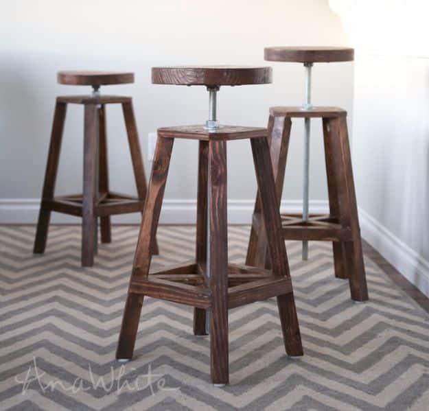 Three industrial adjustable height bar stools with dark walnut stained 2x2 legs and threaded rod seat posts on a rug