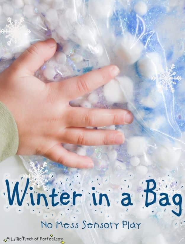 Child's hand pressing on a sealed bag of pale blue gel filled with white marshmallows and snowflake confetti