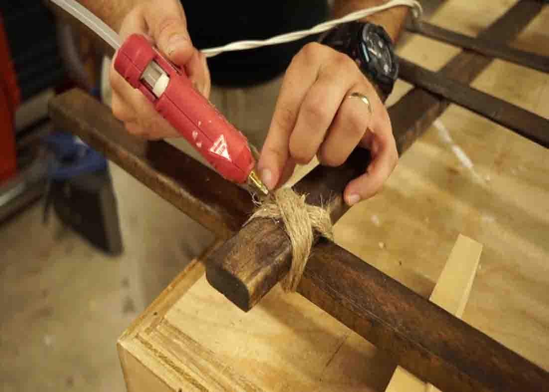 Gluing down the twine to secure the cemetery fence for halloween