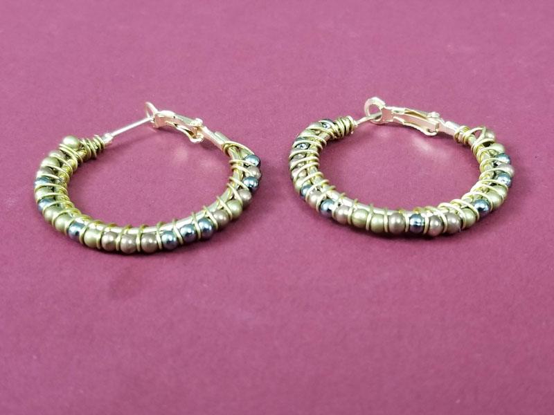 DIY beaded hoop earrings, gold hoops wire wrapped with rows of gold and silver tone beads on a deep pink background