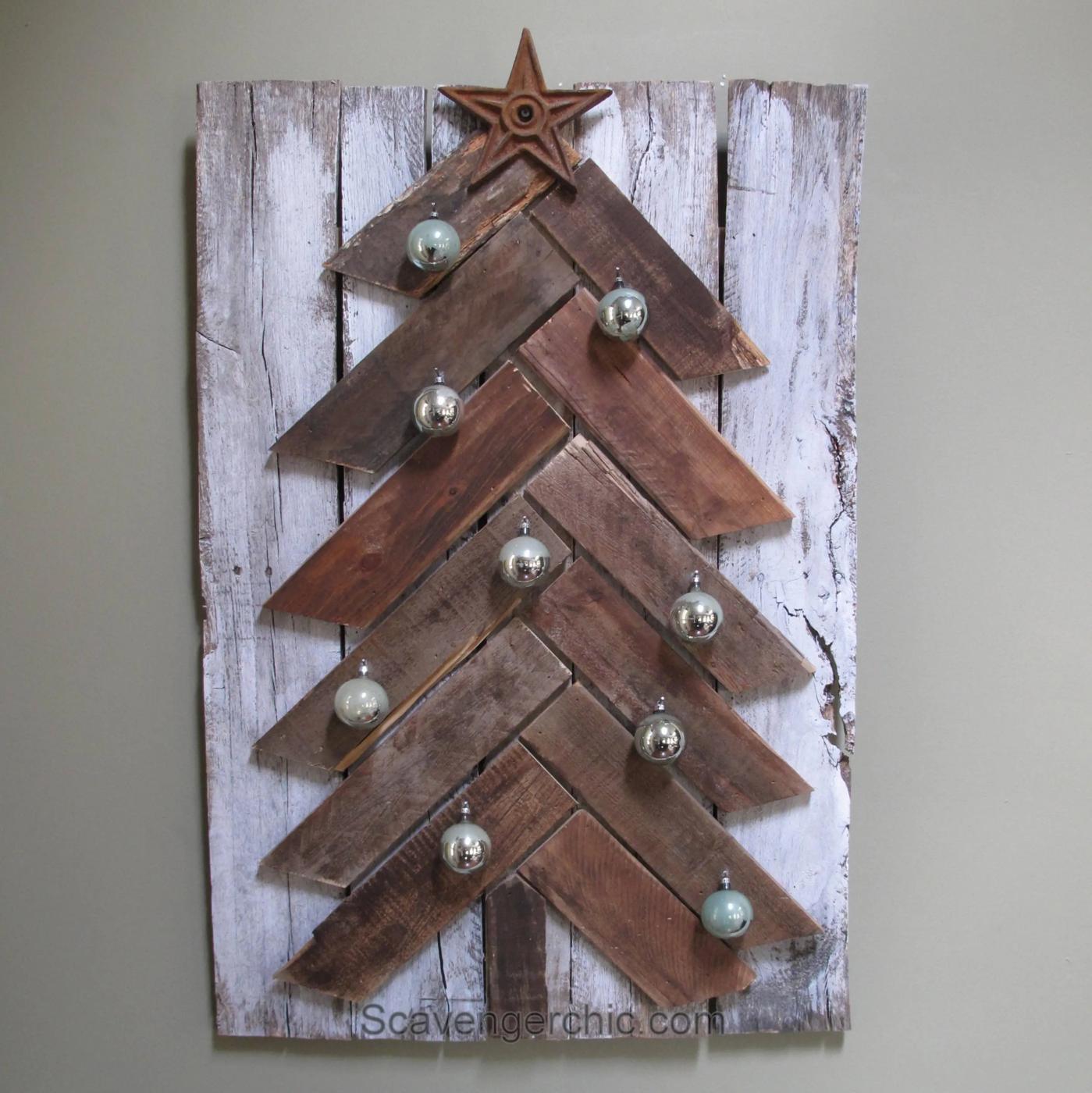 A wall hung Christmas tree of chevron cut pallet boards on a whitewashed pallet backing with a rusty star and ornaments