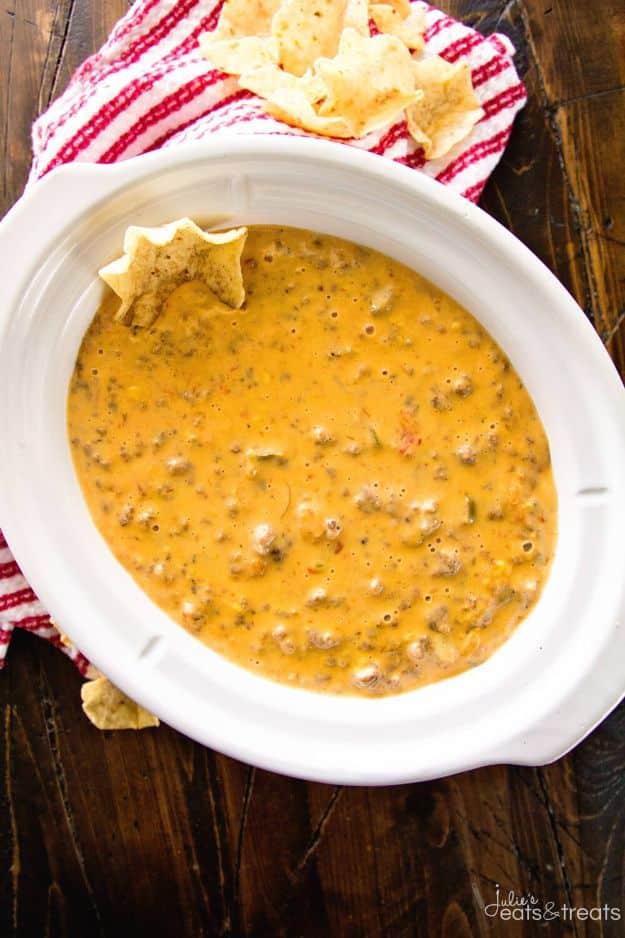 Crock pot cheesy hamburger dip bubbling in a slow cooker with seasoned ground beef through melted cheese