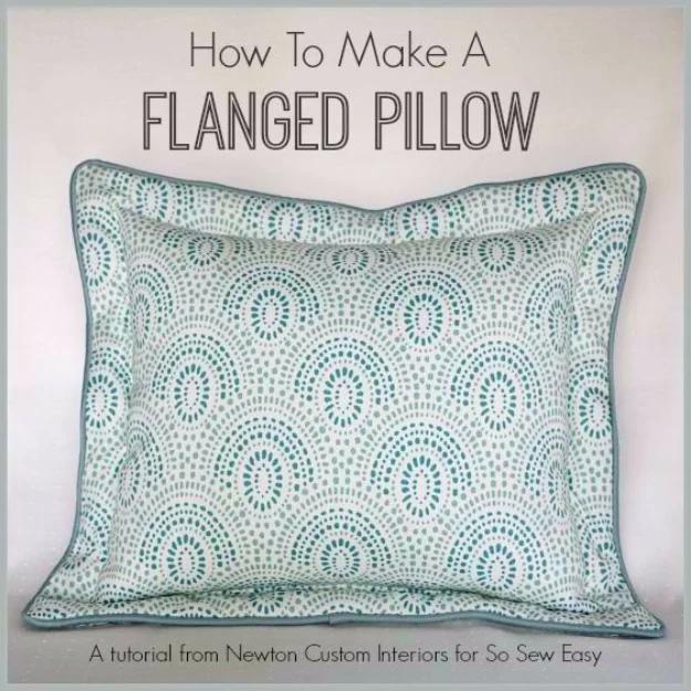 A cream linen flanged pillow on a gray sofa, its flat topstitched border framing the square of heavy woven cloth.