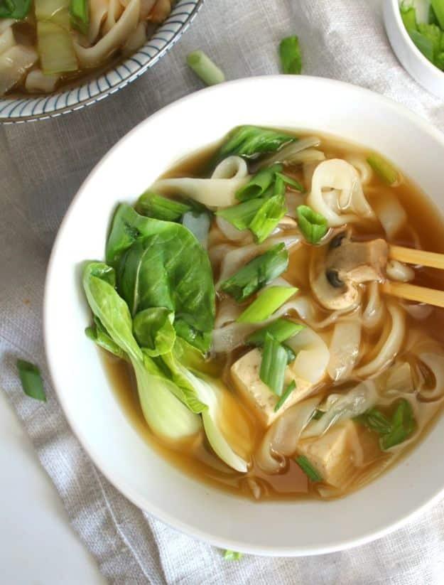 Asian vegetable noodle soup in a white bowl with bok choy, mushrooms, tofu and noodles in dark broth