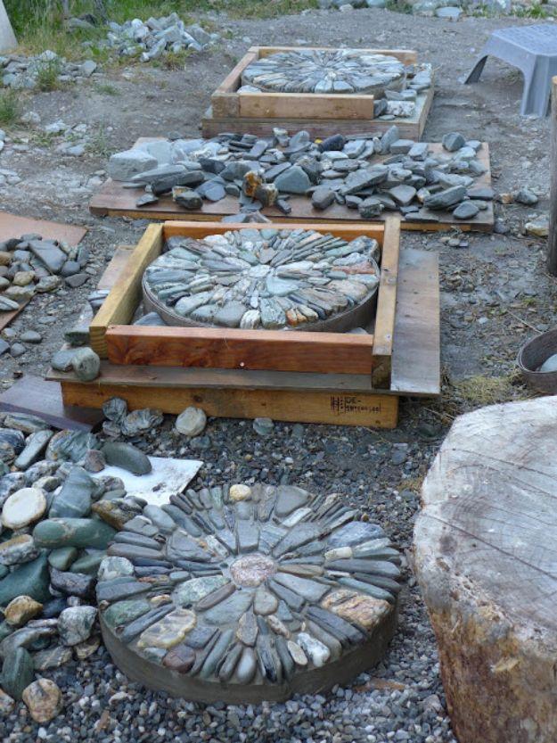 Pebble mosaic stepping stones set in wooden forms with gray stones arranged in spiral and fan patterns
