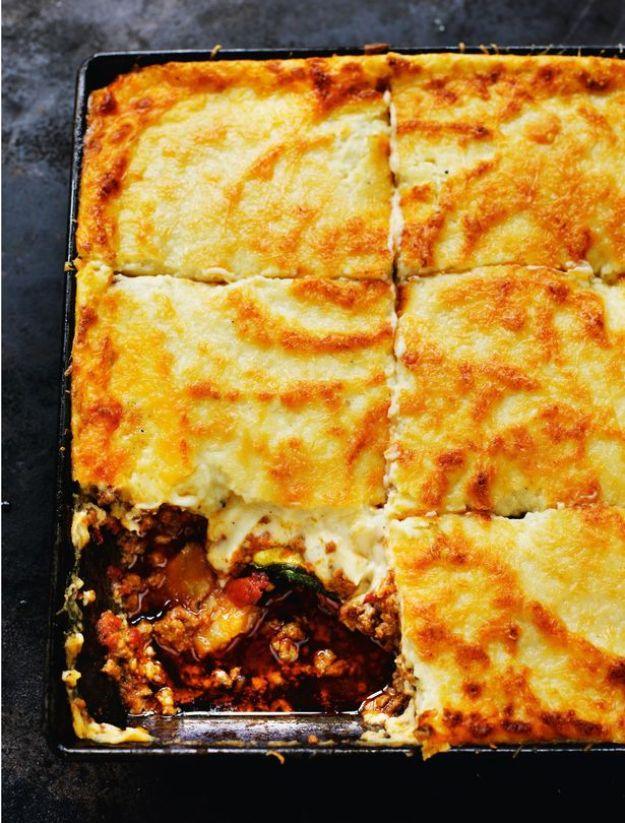 A baked moussaka with a browned bechamel top in a black metal tray, a celebrity inspired Mediterranean recipe