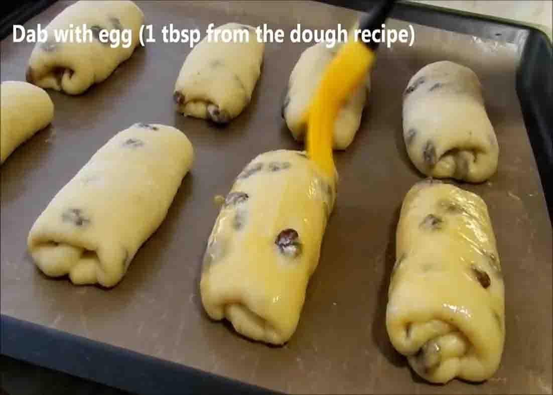 Brushing the top of the raisin bread rolls with beaten egg