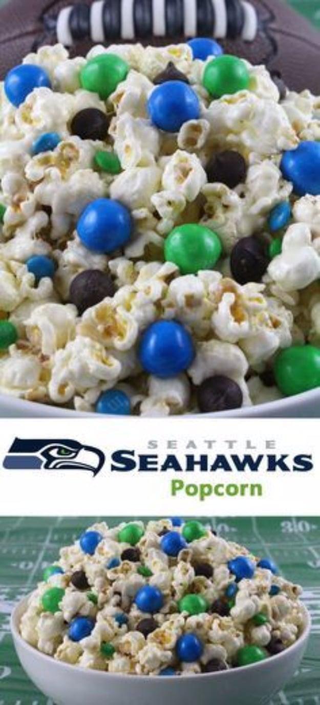 Bowl of marshmallow coated popcorn mixed with blue and green candies, above a Seattle Seahawks popcorn banner
