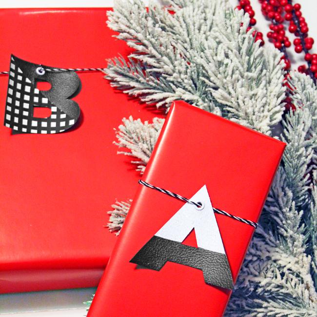 Red wrapped gifts with large faux leather monogram letter tags in black, white and gingham on black twine