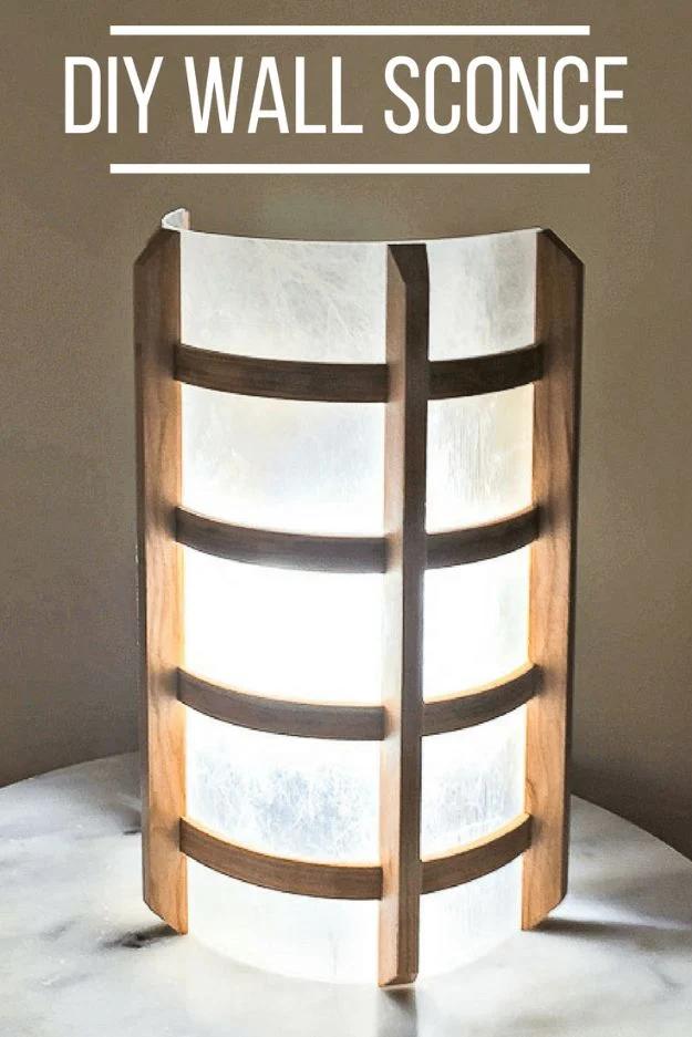 Lit wall sconce of curved dark wood slats over a white rice paper style shade, standing on a marble surface