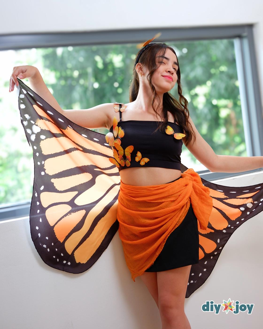 How to Make a Butterfly Costume - woman by a window with one wing outstretched, a butterfly headband and eyes closed laughing