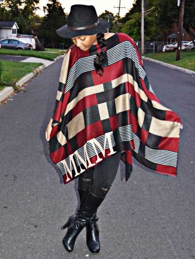 Red, black and cream plaid monogrammed poncho worn with a black hat, ripped jeans and tall leather boots