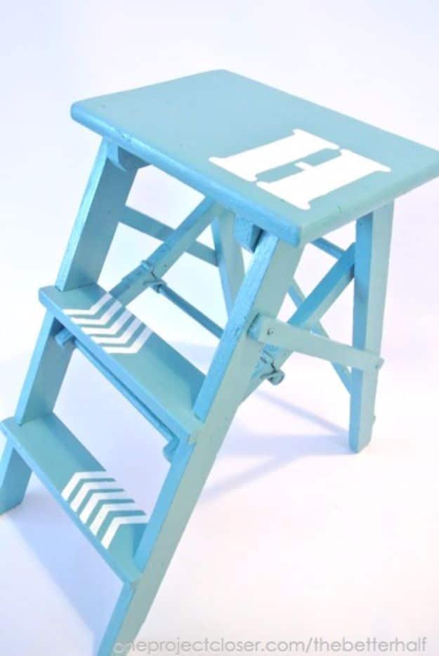 Turquoise painted step stool stenciled with a white letter H on the seat and chevron arrows up the steps