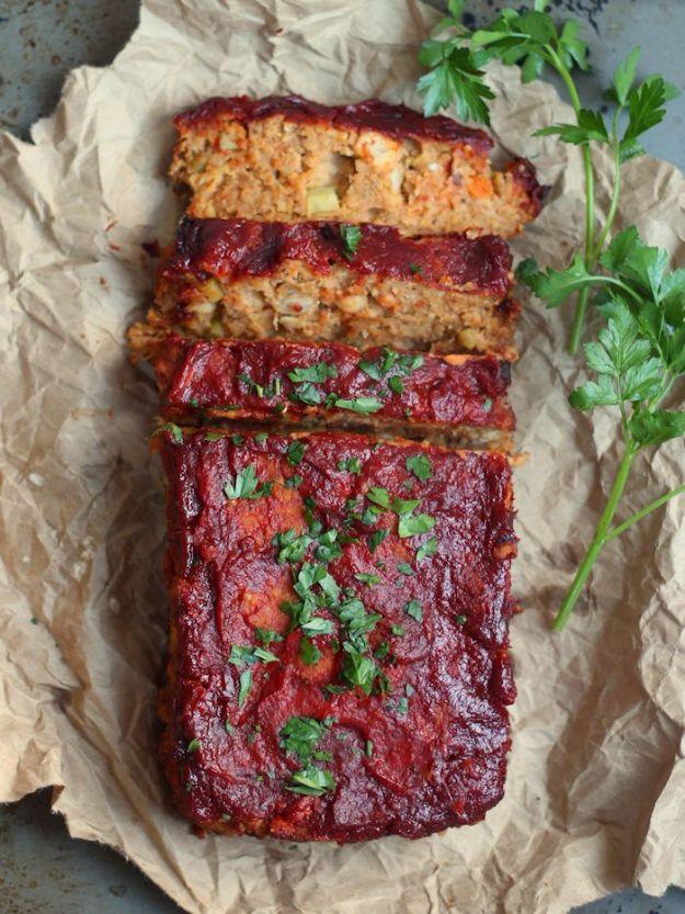 Sliced chickpea vegan meatloaf with a dark maple tomato glaze brushed on top, served on a wooden board