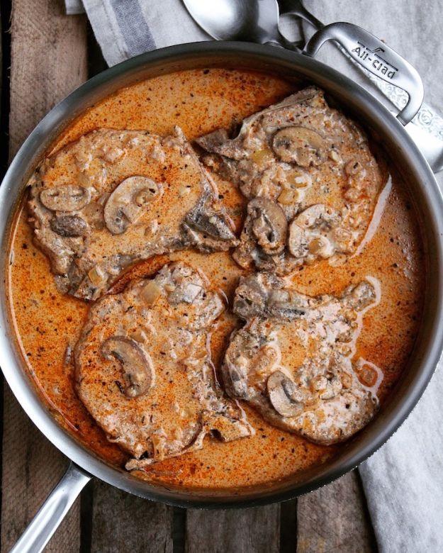 Creamy Cajun braised chops with cremini mushrooms and onions in a rich sour cream sauce in a dark skillet