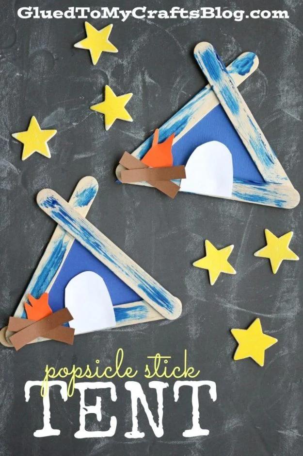 Two popsicle stick tents painted blue on a chalkboard background with paper campfires, doorways and yellow stars