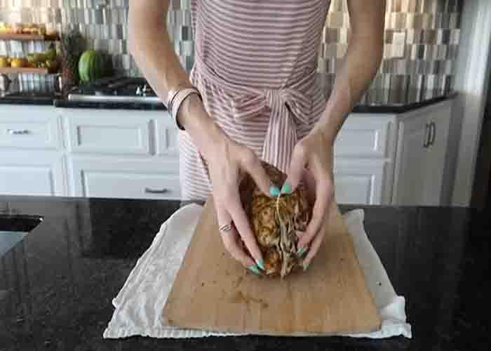 Pushing in the ripe part of the pineapple to loosen the eyes