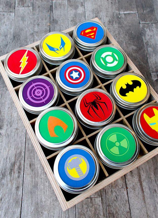 Free printable superhero mason jar lid toppers in twelve emblems on small jars in a divided wooden box