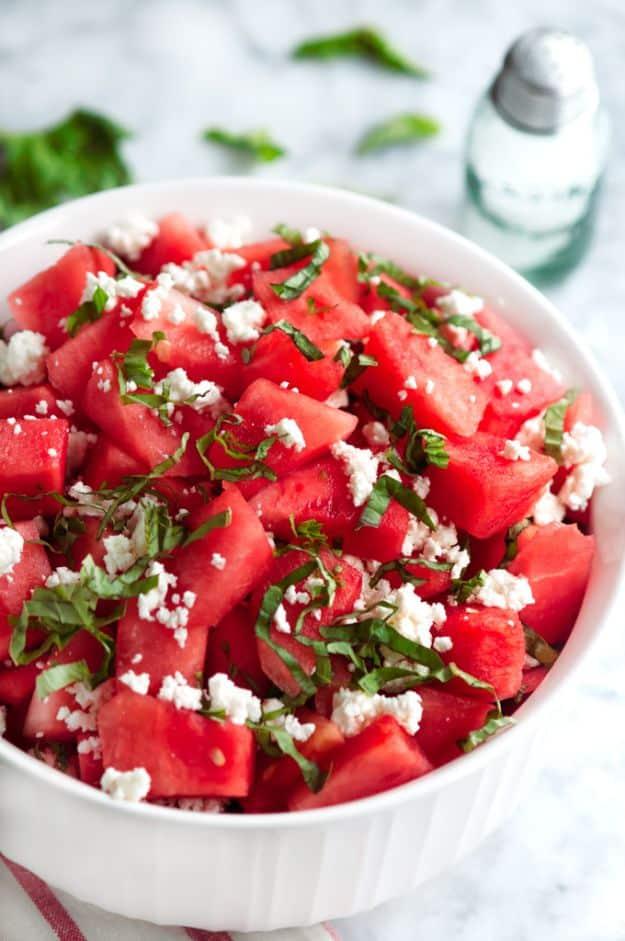 Basil watermelon and goat cheese salad with diced watermelon, crumbled goat cheese and basil in a white bowl