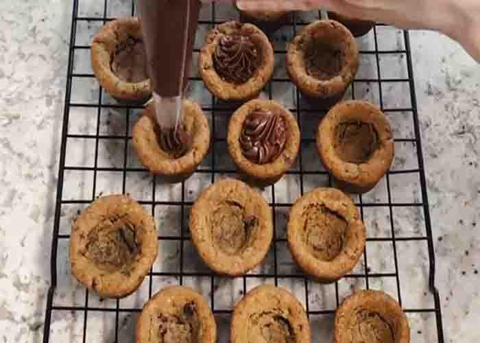 Adding the chocolate frosting on each cookie cup