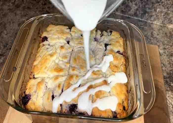 Drizzling the glaze over the blueberry butter swim biscuits