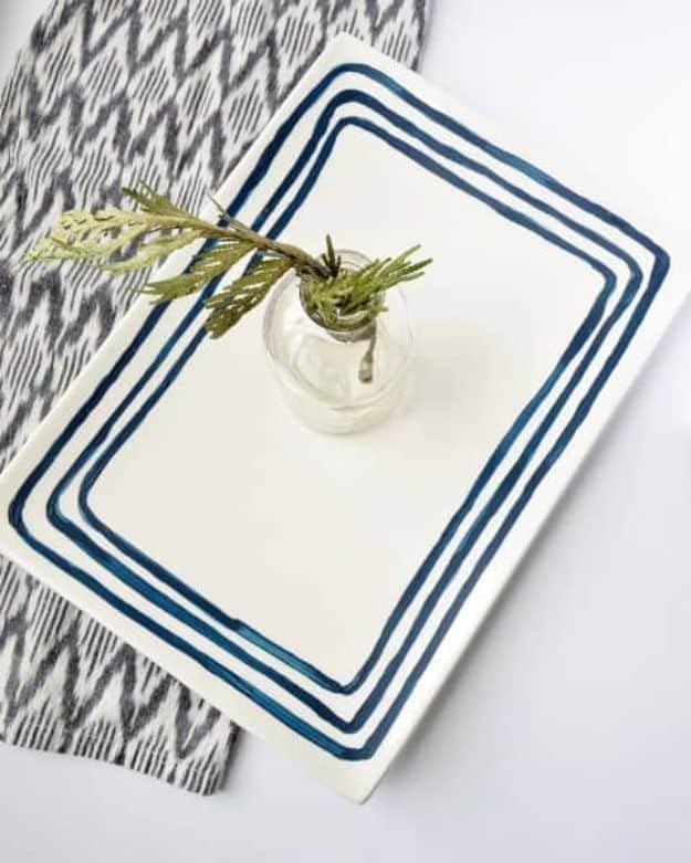 White ceramic tray hand painted with three navy border lines, holding a small bud vase on a patterned cloth