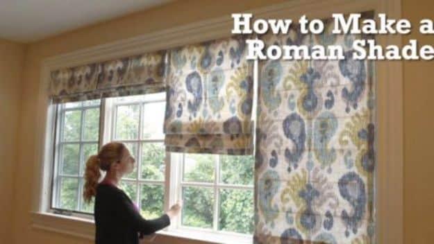 Three ikat print roman shades in blue and gold hung across a bedroom window wall, one raised into folds