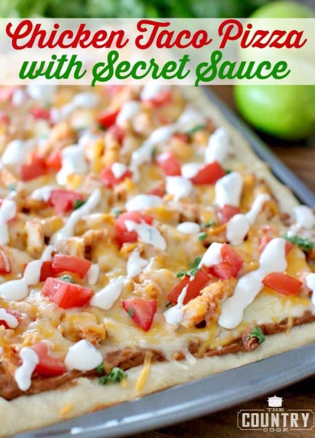 Rectangular chicken taco pizza topped with diced tomato, shredded lettuce and a white secret sauce drizzle