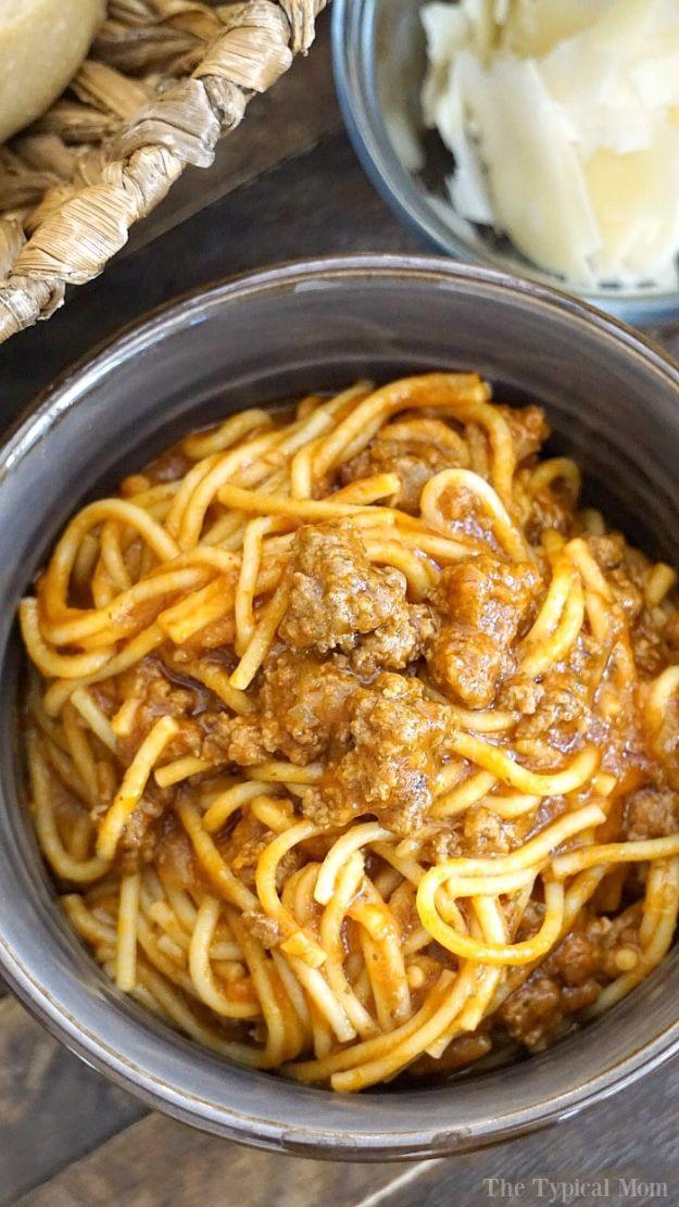 Metal instant pot insert full of spaghetti coated in meat sauce with a bowl of grated parmesan behind it