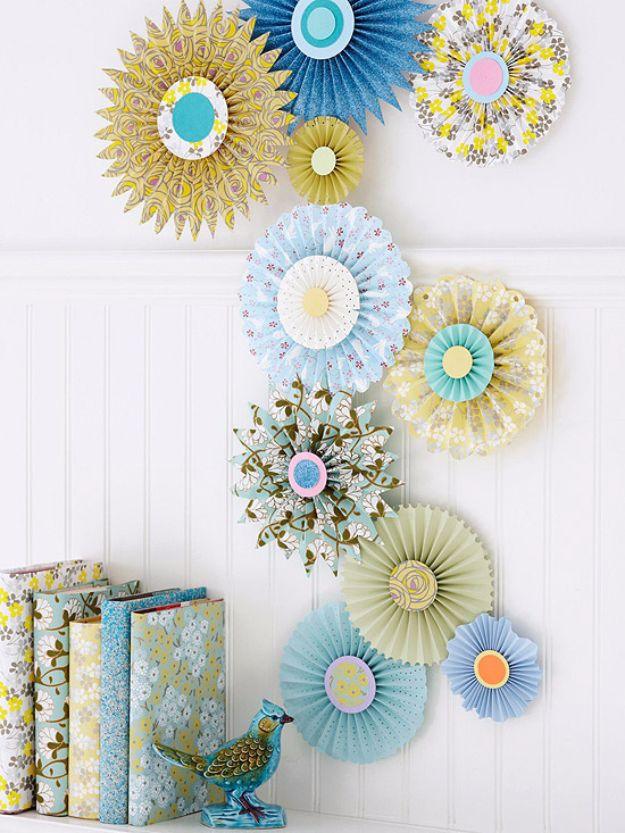 Make pinwheel decorations, a dozen pleated paper rosettes in blue yellow and floral prints arranged on a white panelled wall