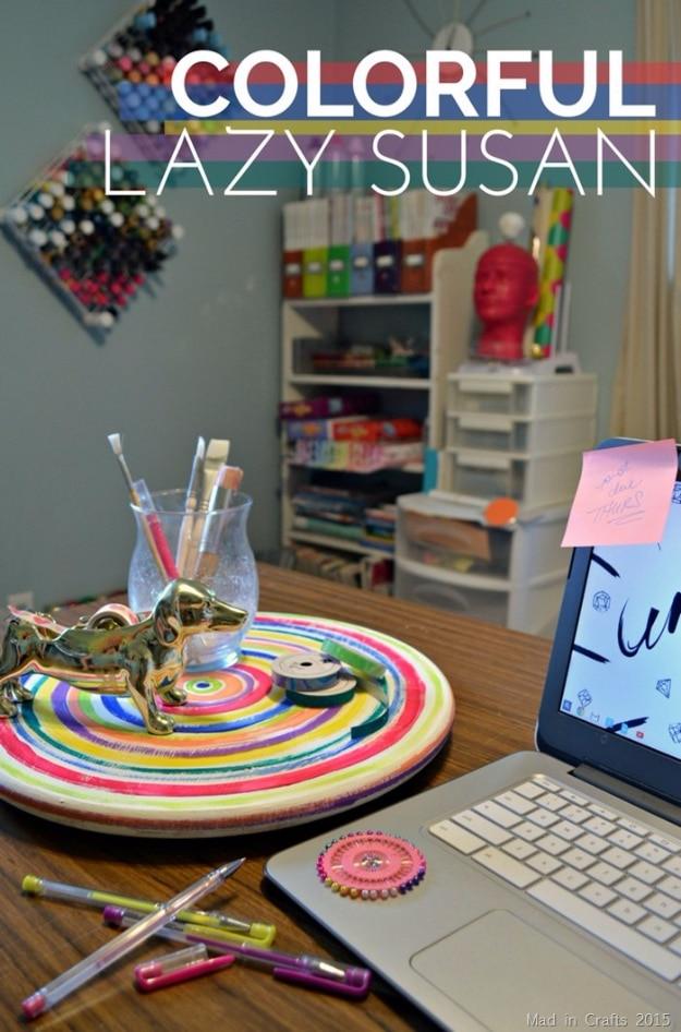 Colorfully painted lazy susan, a rainbow striped wooden turntable on a desk holding pens beside a laptop