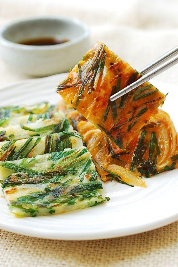 Korean garlic chive pancakes cut into squares on a white plate with chopsticks and a soy dipping sauce