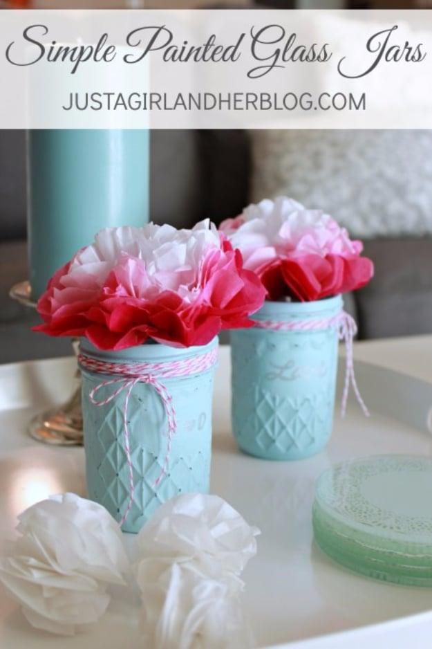 Glass jars painted on the inside in solid pink and white standing in a row as handmade gifts on a craft table